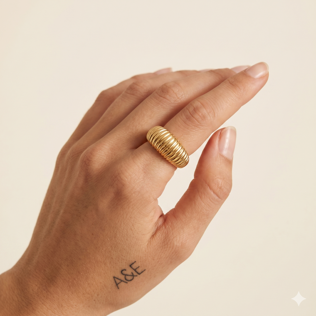 Hand wearing a gold ring with a beige background