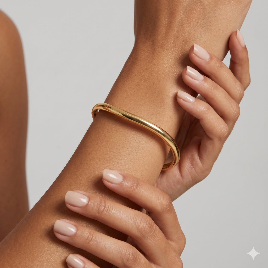 Gold bracelet on a wrist with a neutral background