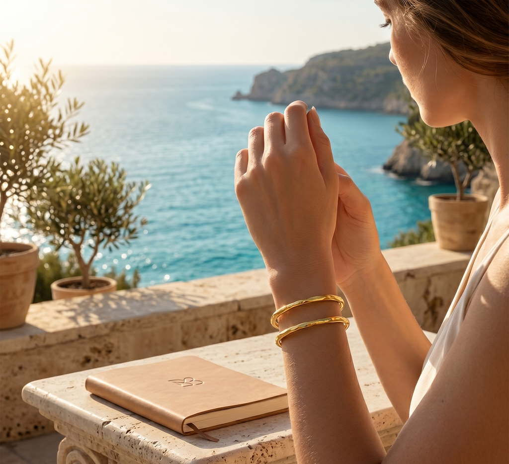 Woman with gold bracelets praying by a scenic ocean view