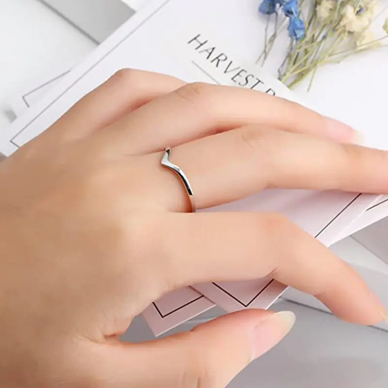 Hand wearing a silver ring with a blurred background